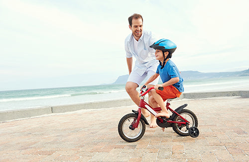 Father and son learning to ride a bicycle at the beach having fun together,I love you all the same