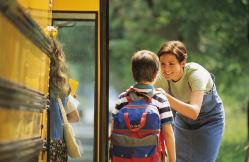 Mother sending son off to school at bus stop