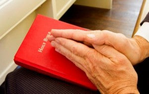 The-Surprising-Benefits-of-Praying-Alone. An image of hands praying over a Bible.