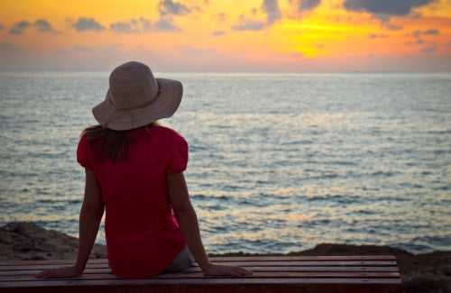 Young woman in hat sitting and looking to the sunset,Unfading beauty of a gentle and quiet spirit which is of great worth in God's sight