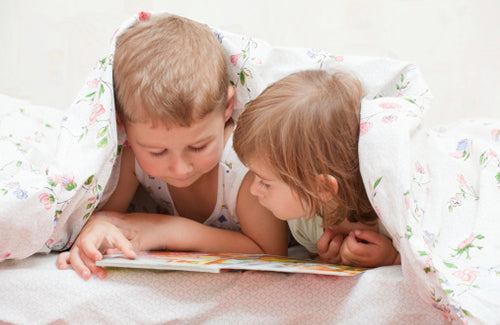 brother and sister, reading a book, on the bed