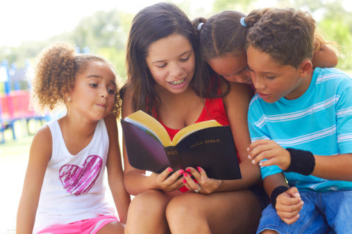 Teenage Girl Reading Bible To Siblings At Park,summer routine for kids,shine your light girls devo thomas nelson
