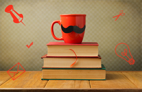 Vintage books and cup with mustache on wooden table over retro background