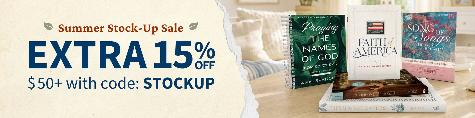 Promotional banner for a summer stock-up sale featuring large blue and red text on the left and a styled photo of several books on a table to the right, including titles such as Prayer for the Names of God, Faith of America, and Song Stories.