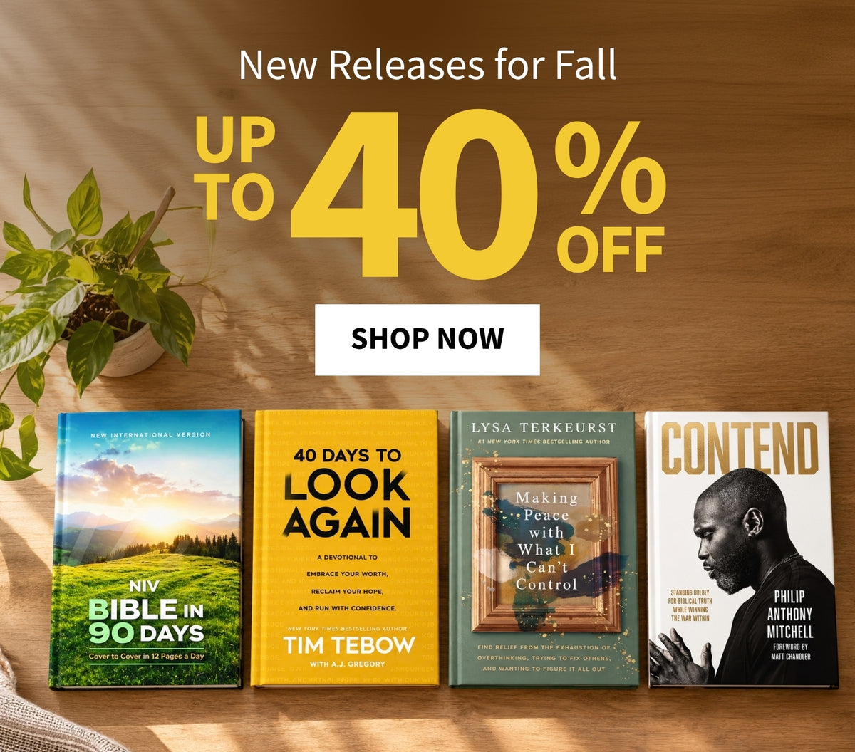 Promotional banner for fall book releases showing four physical books on a wooden surface with a potted plant and large text reading 'New Releases for Fall,' 'UP TO 40% OFF,' and 'SHOP NOW.' Visible book covers include 'NIV Bible in 90 Days' by Niv Bible, '40 Days to Look Again' by Tim Tebow, 'Making Peace with What I Can't Control' by Lysa Terkeurst, and 'Contend' by Philip Anthony Mitchell.